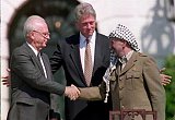 US President Bill Clinton (c) stands between PLO leader Yasser Arafat (r) and Israeli Prime Minister Yitzahk Rabin (L) as they shake hands for the first time, on September 13, 1993 at the White House in Washington DC, after signing the historic Israel-PLO Oslo Accords on Palestinian autonomy in the occupied territories. J. DAVID AKE / AFP