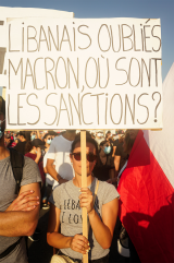 Une manifestante brandit une pancarte appelant le président français Emmanuel Macron à prendre des sanctions contre les hommes politiques libanais. Crédit photo : Ines Gil